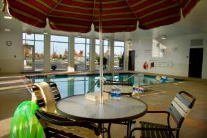 a table and chairs with an umbrella next to a swimming pool at Hyatt Place South Bend/Mishawaka in South Bend