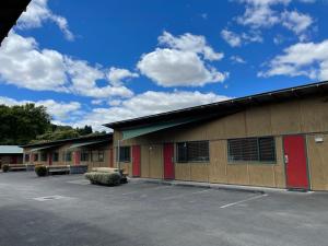 a building with red doors and a parking lot at Waitomo Lodge in Te Kuiti