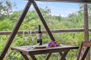 Una botella de vino y dos copas en una mesa. en Glamping Serra da Canastra - Casinha de Hortelã - Domo Embaúba, en Delfinópolis