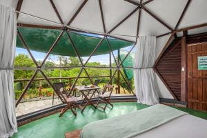 um quarto com uma cama, uma mesa e uma janela em Glamping Serra da Canastra - Casinha de Hortelã - Domo Embaúba em Delfinópolis