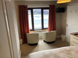 ein Schlafzimmer mit zwei weißen Stühlen vor einem Fenster in der Unterkunft Marine House Holiday Home in Portree