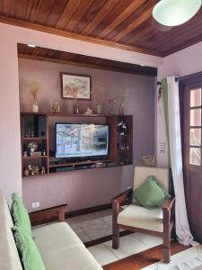 a living room with a tv and a couch and a chair at Casa em Paraty a 7 min. do Centro histórico in Paraty