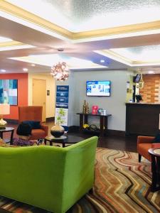 a lobby with a green couch and a tv at Best Western Plus Universal Inn in Orlando