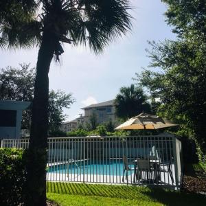 una valla con sombrilla y sillas junto a una piscina en Best Western Plus Universal Inn, en Orlando