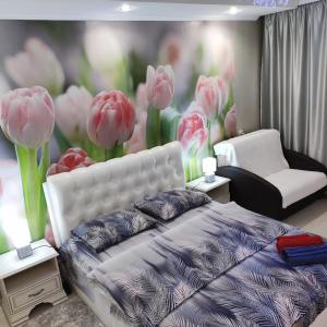 a bedroom with a bed and a painting of pink tulips at уютные апартаменты на Брестской 171 in Pinsk