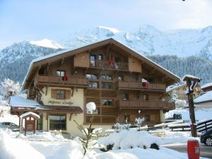 un grand bâtiment en bois avec de la neige au sol dans l'établissement Alpine Lodge 6, aux Contamines-Montjoie