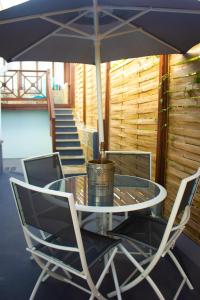 a glass table with two chairs and an umbrella at Les Bougainvilliers Tropicaux in Sans Pareil