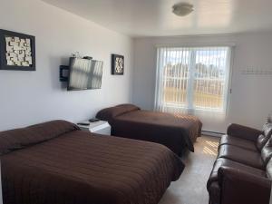 Habitación de hotel con 2 camas y sofá en Les studios de la mer, en Matane