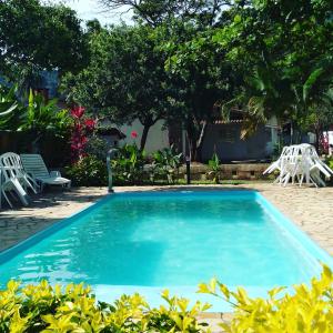 uma piscina num quintal com cadeiras e árvores em Hotel Portal da Praia em Barequeçaba