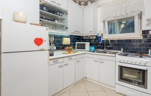 kuchnia z białymi szafkami i białą lodówką w obiekcie House Noa w mieście Malinska