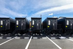 una fila de contenedores negros en un estacionamiento en HOTEL R9 The Yard Inabe, en Kuwana