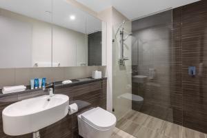 a bathroom with a sink, toilet and bathtub at Meriton Suites Mascot Central in Sydney