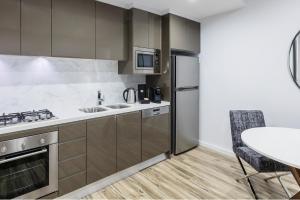 a kitchen with a refrigerator, stove, sink and microwave at Meriton Suites Mascot Central in Sydney
