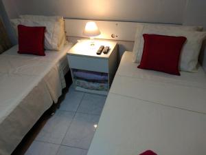 a bedroom with two beds with red pillows and a lamp at Recanto do Parque in Campo Grande