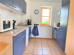 a kitchen with blue cabinets and a tile floor at Ferienwohnung Am Wundergraben inkl. Chiemgaukarte in Ruhpolding