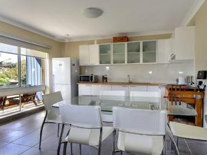 a kitchen with a glass table and white chairs at Beachside Getaway in Kiama