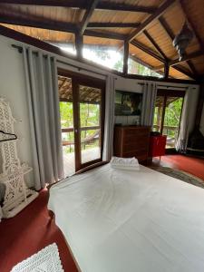 a bedroom with a large white bed and windows at Bangalô na Natureza in Nova Friburgo