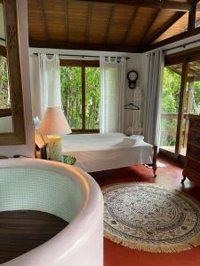 Bangalô na Natureza في نوفا فريبورغو: غرفة نوم مع سرير وحوض استحمام في غرفة