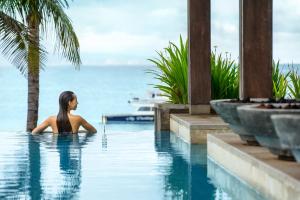サヌールにあるInterContinental Bali Sanur Resort, an IHG Hotelの海を見渡すスイミングプールに座る女性