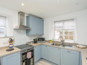 a kitchen with blue cabinets and a sink at The Pink House in Rhosneigr