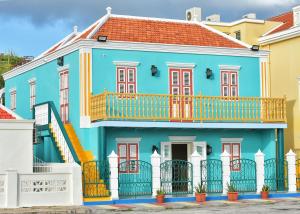 a blue house with a balcony at Turquoise B&B in Willemstad