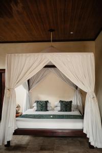 a bed with a canopy in a room at Mandala Desa in Sukawati