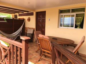 a porch with a wooden table and chairs at Kay Ghislaine in Les Anses-dʼArlets