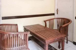 mesa de madera, 2 sillas y banco de madera en Risqia Syariah TOD M1 Bandara Soekarno Hatta Mitra RedDoorz en Sewan