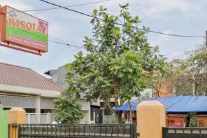 una señal frente a un edificio con un árbol en Risqia Syariah TOD M1 Bandara Soekarno Hatta Mitra RedDoorz en Sewan