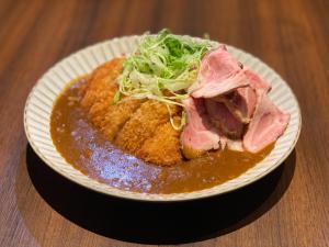 a plate of food with meat and salad on a table at APA Hotel Keikyukamata Ekimae in Tokyo