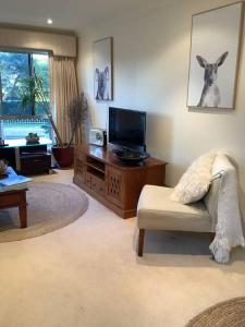 a living room with a tv and a living room with a couch at Maggie's Nest-Come & Rest in Killarney Vale