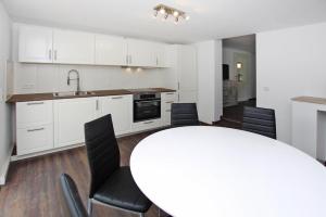 een keuken met witte kasten en een witte tafel en stoelen bij Cottage, Plau am See in Plau am See