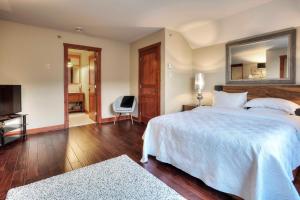 a bedroom with a large white bed and a mirror at Les Eaux - 2bdrs W Pool & Hot Tub Near Village 5 in Mont-Tremblant