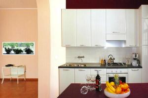 a kitchen with white cabinets and a bowl of fruit on a table at Holiday home, Castiglione di Sicilia in Castiglione di Sicilia