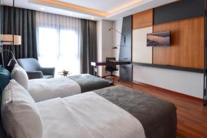 a hotel room with two beds and a desk at Expoist Hotel in Beylikduzu