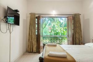 a bedroom with a bed and a television and a window at Villa Barbosa, 2 BHK Villa & Luxury Rooms near Colva, Sernabatim, Benaulim Beach in Colva