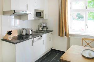 a kitchen with white cabinets and a sink and a window at Mansion in Garz with garden in Garz-Rügen