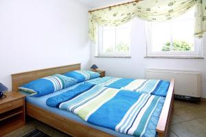 a bedroom with a bed with blue sheets and two windows at Apartments Jeske Altenkirchen in Altenkirchen
