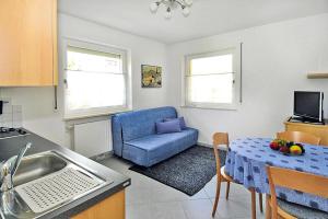 Il comprend une cuisine et un salon avec une chaise bleue et une table. dans l'établissement Apartment in Schlanders with terrace, à Silandro
