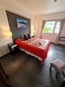 - une chambre avec un lit doté d'une couverture rouge et d'une fenêtre dans l'établissement PlaceresCC, à Ushuaia