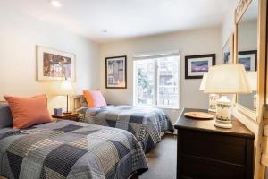 a bedroom with two beds and a table with a lamp at All Seasons Walk To Lifts in Vail +4 photos
