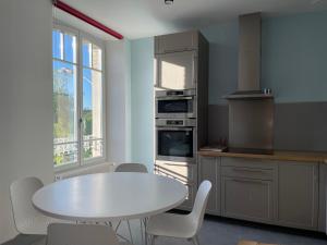 uma cozinha com uma mesa branca, uma mesa e cadeiras em Marelle // bleu em Courmelois