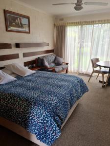 a person laying on a bed in a bedroom at Toora Lodge Motel in Toora