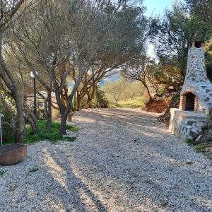 a gravel road with a stone fireplace next to trees at Hotel Valle del Cedrino in Galtellì