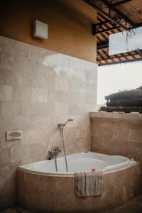 a bath tub with a shower in a bathroom at Mandala Desa in Sukawati