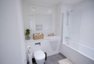 a white bathroom with a toilet and a shower at Virexxa Bedford Centre - Deluxe Suite - 2Bed Flat with Free Parking & Gym in Bedford