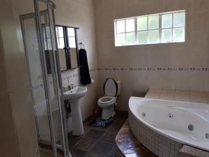 ein Badezimmer mit einer Badewanne, einem WC und einem Waschbecken in der Unterkunft QUARTERDECK VILLA in Deneysville