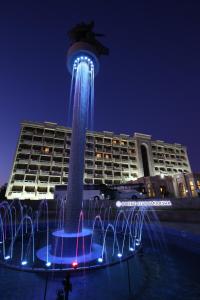 uma fonte de água em frente a um edifício à noite em Orient Star Varaxsha em Bukhara