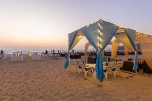 a group of tables and chairs on a beach at Amara Oceanfront Resort & Club Baga in Baga