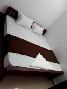 2 camas en una habitación con sábanas y almohadas blancas en Emirates Residency, en Pudunagaram